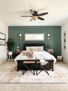 a bedroom with green walls, white bedding and a ceiling fan in the corner