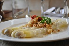 a white plate topped with banana slices covered in sauce and garnished with crumbs