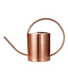 a copper colored watering can with a long handle on the side and a curved top