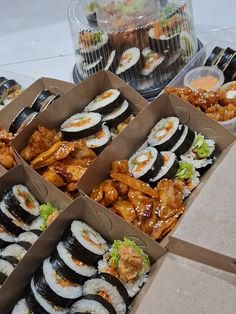 several boxes filled with different types of sushi and other foods on top of a table