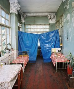 two beds with blue tarp covering them in a room that has wooden floors and walls