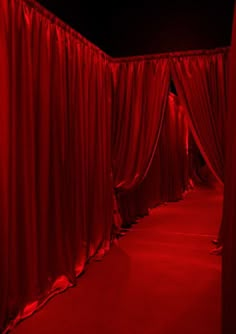 a red room with drapes covering the walls and floor, in front of a black background