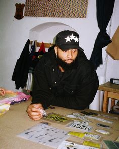 a man sitting at a table in front of papers and stickers on the table