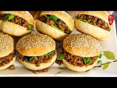 several sandwiches are arranged on a plate with sesame seed crusts and lettuce