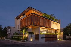 a modern house is lit up at night with plants growing on the roof and windows