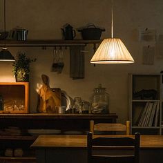 the kitchen is dimly lit and has many items on the counter top, including a wooden table with two chairs