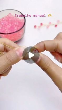 someone is making something out of beads with their fingers and thumbnails while another person holds the bead