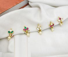 three pairs of earrings sitting on top of a white cloth next to an open book