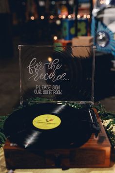 a record player sitting on top of a wooden table next to a sign that says be the reason