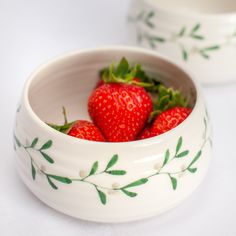 two white bowls with strawberries in them