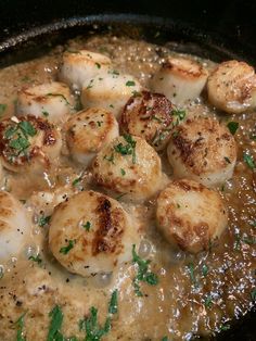 some scallops are being cooked in a brown gravy with parsley