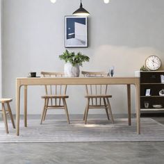 a dining room table with chairs and a clock on the wall