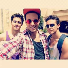 three young men taking a selfie in front of a building with their arms around each other