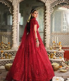 a woman in a red wedding gown standing on the floor with candles and flowers around her