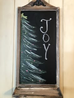 a chalkboard with the word joy written on it in front of a christmas tree