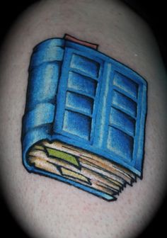 a blue book tattoo on the back of a woman's shoulder