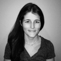 a black and white photo of a woman with long dark hair smiling at the camera