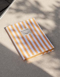 an orange and white striped paper bag sitting on top of a table next to a tree