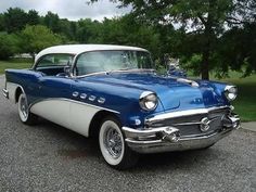 an old blue and white car parked on the street