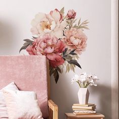 a pink bed with flowers painted on the wall behind it and a white vase filled with flowers