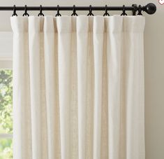 a white curtain with black metal rods hanging from it's side in front of a window