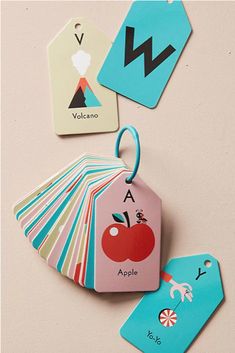 four tags with different designs on them and one has an apple hanging from it's side