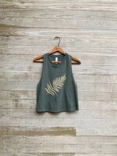 "this is my go to workout top as it pairs well with leggings for my yoga, barre or running workouts. i print my fern design in gold on this ultra cool green tank which has nice open armholes for venting all that sweat and to show off your arms! COLOR: evergreen S: chest 34\", length 19\" M: chest 36, length 20\" L: chest 38\", length 21\" XL: chest 40-42\", length 23\"" Cheap Vintage Tops For Outdoor, Clothes On Sale, Spring Graphic Print Crop Top For Workout, Spring Yoga Tank Top With Crew Neck, Green Crew Neck Workout Tank Top, Spring Crew Neck Crop Top For Yoga, Spring Yoga Crop Top With Crew Neck, Green Cropped Tank Top For Workout, Fern Design