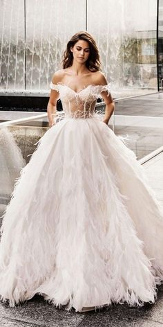 a woman in a white wedding dress standing on the street with her hand on her hip