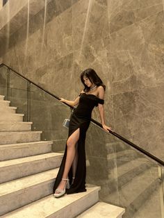 a woman in a black dress standing on some stairs