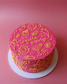 a pink and yellow cake sitting on top of a white plate next to a pink wall