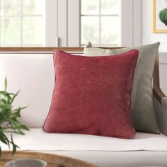 a couch with two pillows on top of it next to a table and potted plant