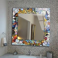 a bathroom with a sink, mirror and mosaic tile on the wall above it's faucet