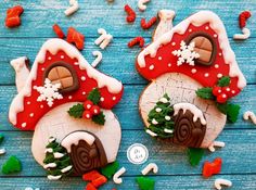 two decorated cookies sitting on top of a blue wooden table covered in white and red icing