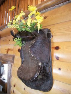 a horse saddle with flowers in it hanging on the wall