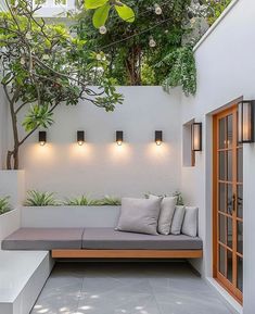 an outdoor seating area with potted plants and lights on the wall, along with concrete flooring