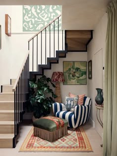 a living room filled with furniture and a stair case next to a painting on the wall