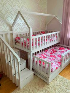 a white bunk bed with pink bedspread on top and stairs to the bottom