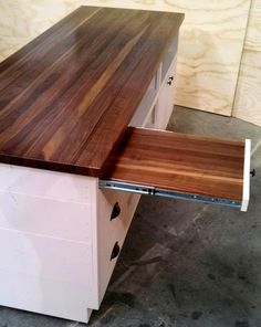 a wooden counter top sitting on top of a white cabinet