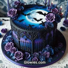 there is a cake decorated with purple roses and bats on the table next to candles