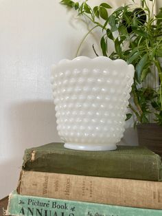 a white vase sitting on top of a stack of books