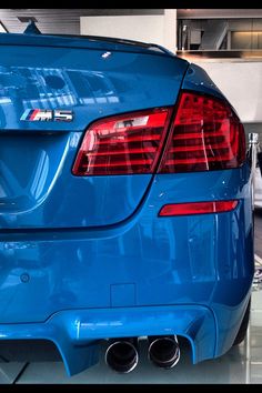 the rear end of a blue car in a showroom