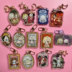 a bunch of anime key chains on a pink surface with some pictures hanging from them