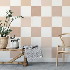 two potted plants sit on a table in front of a checkered wall