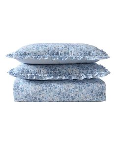 three pillows stacked on top of each other in front of a white background with blue flowers