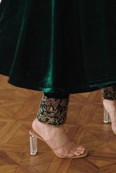 the legs and ankles of a woman wearing high heeled sandals, in green velvet