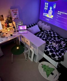 a room with a bed, desk and laptop computer on it in front of a projector screen