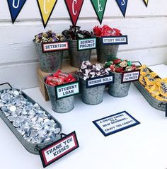 a table topped with buckets filled with candy and candies next to bunting flags