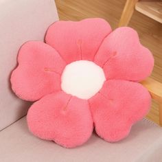 a pink flower shaped pillow sitting on top of a couch