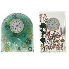 two clocks sitting next to each other in front of a card holder with flowers on it