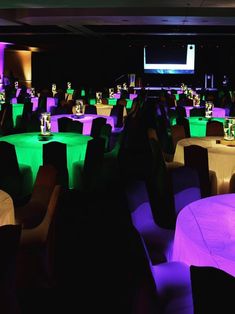 a room filled with lots of tables covered in green and purple lights